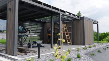 Çağdaş bir bahçe kulübesi yapmak çevre düzenlemeli bir alanda bitki ve aletlerin yer aldığı. İnşaat, organizasyon ve estetik cazibeyi ön plana çıkarıyor.