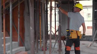 Sert şapka takan işçiler, gündüz saatlerinde bir inşaat sahasına yapısal destek yerleştirmekle meşgul oluyor..