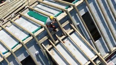 Bir inşaat işçisi, gündüz saatlerinde devam eden bir inşaat projesine malzeme yerleştirmek için bir çatı yapısına yerleştiriliyor..