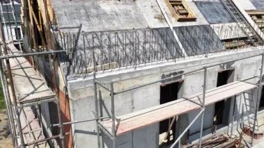 İşçiler, gelişmekte olan bir mahallede, çelik iskelet ve iskelenin sergilendiği çok katlı bir konut inşaatı ile aktif olarak ilgileniyorlar..