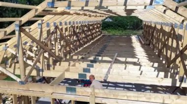 İnşaatçılar parlak bir yerde ahşap bir çerçeve oluşturuyorlar, açık mavi gökyüzü altında karmaşık tasarım ve işçiliği sergiliyorlar..