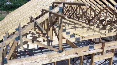 Tahta kirişler, güneşli bir günde sakin bir kırsal alanda sağlam bir çatı iskeleti oluşturmak için dikkatlice toplanır..