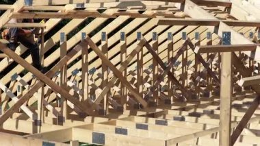 İnşaatçılar ahşap kirişleri ve kirişleri dikkatle bir çatı için birleştiriyor, inşaat tekniklerini ve gündüz çalışmalarını sergiliyorlar..