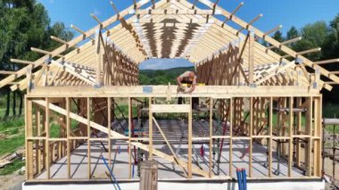 İşçiler, temiz mavi gökyüzünün altına ahşap bir çerçeve inşa ederek, işçiliğini ve güzel bir kırsal alanda ilerlemesini sergiliyorlar..