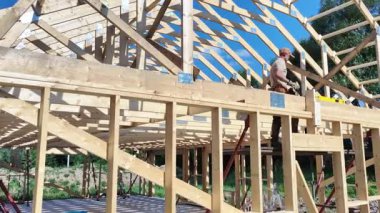 Yetenekli bir marangozun parlak güneşin altındaki bir ev için ahşap bir çerçeve inşa edişini izleyin. Etkileyici bir işçilik ve detaylara dikkat göstermektedir..