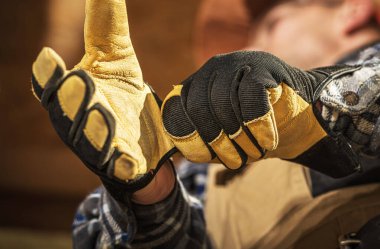 Koruyucu eldivenlerdeki işçiler, kırsal bir atölye ortamında marangozluk projesi için gerekli aletleri hazırlarken düzgün kavrama ve kontrol gösterileri sergiliyor.