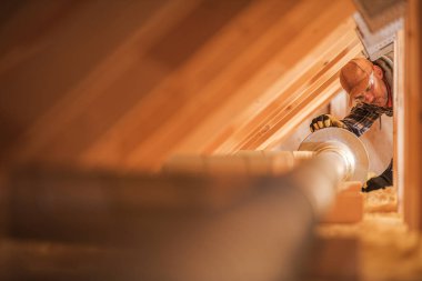 Bir marangoz titizlikle tavan arasına doğal ışıkla dolu bir havalandırma sistemi kurar. Yetenekli işçi elimizdeki işe odaklanmış durumda..