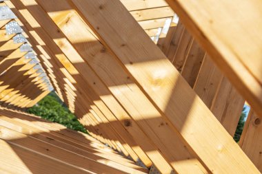 Ahşap bir çerçeveye yakından bakmak, gün ışığının filtrelediği karmaşık desenleri ve gölgeleri ortaya çıkarır, işçiliği ve tasarım elementlerini vurgular..