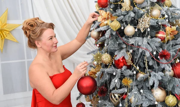 聚焦优雅的女性举行红色圣诞球 同时考虑它在树枝上的合适位置 用玩具装饰冷杉树的快乐女人 — 图库照片
