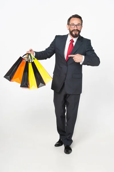 stock image Full length portrait of a businessman wearing glasses and suit smiling and pointing with finger to the bunch of shopping bags holded in hand isolated on white background