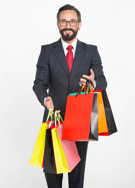 40s Attractive Sales Man carrying and showing colored shopping bags isolated on white. Handsome man wearing suit and holding shopping papper bags in hands. Man shopping time for presents.