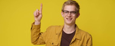 Sarı kot ceketli, gülümseyen, sarı arka planda yalnız poz veren çekici, genç 20 'li yaşlarda komik bir adam. Kızıl gencin portresi. İnsanlar yaşam tarzı kavramını işaret ediyor.