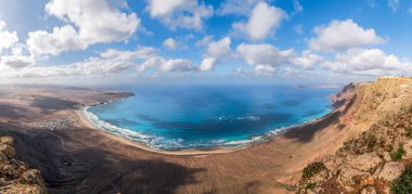Playa Famara ve Lanzarote 'nin gökyüzü suları ve dramatik uçurumlar tarafından kucaklanan altın kumları, bir sörfçü cenneti..