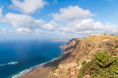 Playa Famara ve Lanzarote 'nin gökyüzü suları ve dramatik uçurumlar tarafından kucaklanan altın kumları, bir sörfçü cenneti..