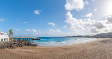 Landscape with Arrieta Beach in Lanzarote, Canary Islands, featuring a sandy shore, crystal-clear waters, and stunning coastal views clipart