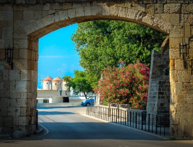 Eski Rodos kasabasına ortaçağ taş kemeri, canlı bir bougainvillea ve çarpıcı bir sahil manzarası ile yel değirmenleriyle gir.