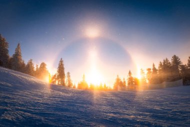 Capture the beauty of a rare sun halo over a snowy ski slope in Poiana Brasov. Perfect for winter sports, nature, and atmospheric phenomena enthusiasts. clipart