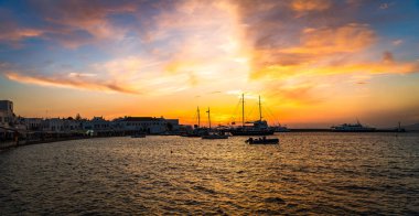 Yunanistan 'ın Mykonos Town (Chora) üzerinde gün batımı, Ege Denizi' ni yansıtan altın renklerle. Limanın manzarası, yatlar ve ikonik beyazlatılmış binalar..