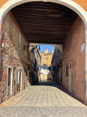 Kemerleri, tuğlaları ve güneşte asılı çamaşırları olan Venedik caddesi, otantik ve resimsi atmosfer.