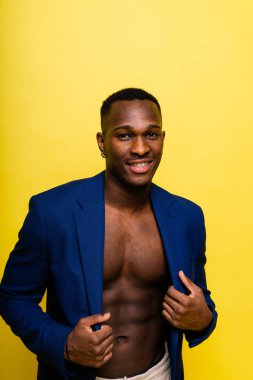 Guy in blue suit on a yellow background. Handsome athletic man in jacket smiling