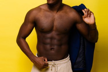 Guy in blue suit on a yellow background. Handsome athletic man in jacket smiling