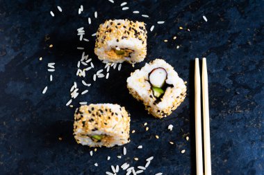 Ahşap çubuklarla siyah masada suşi. Restoranda Japon yemeği yemek..