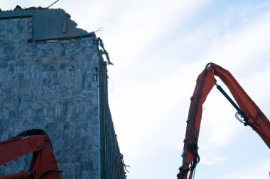 Demolition of a old building with sloopkraan against blue clouds sky.