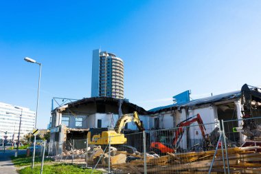 Demolition of a old building with sloopkraan against blue clouds sky.