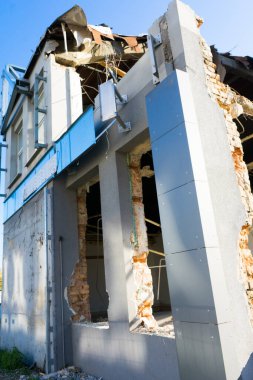 Demolition of a old building with sloopkraan against blue clouds sky.