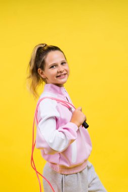 Adorable female child with skipping rope jumping in a studio