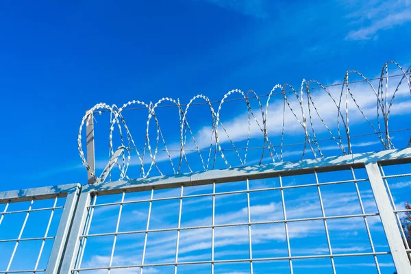 Barbered wire over blue sky and on building ground, rusty