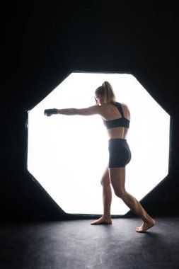 Woman Boxer In Gloves Training On a black, red, yellow Background
