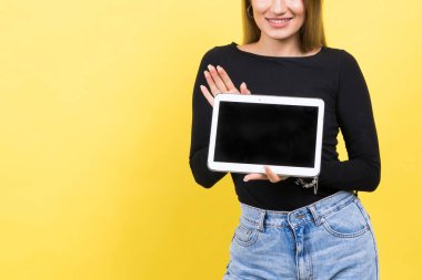 Sarı arka planda izole edilmiş dijital tablet kullanan zeki beyaz kadın öğrenci.