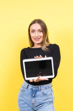 Sarı arka planda izole edilmiş dijital tablet kullanan zeki beyaz kadın öğrenci.