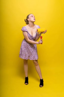 Young classic pin-up woman painting wall with a paint roller