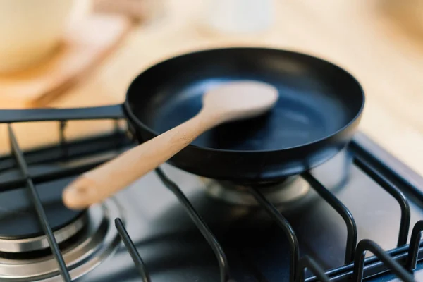 Spatula in a skillet teflon coating pan on gas stove against spoon hanging in small kitchen