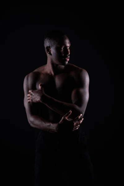 One young african muscular build man standing topless silhouette isolated on a black background