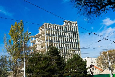 Demolition of a old building with sloopkraan against blue clouds sky.