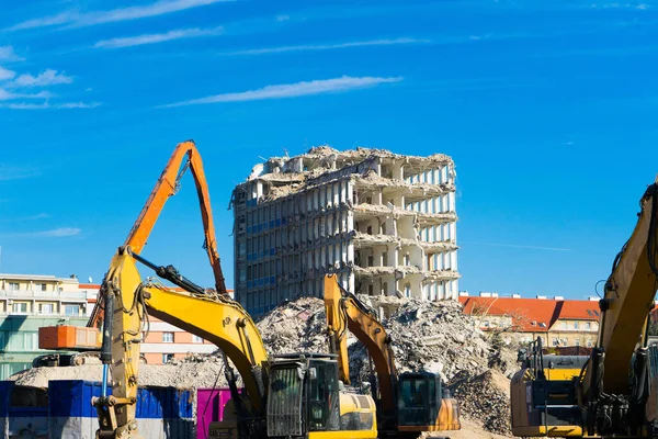 Demolition of a old building with sloopkraan against blue clouds sky.