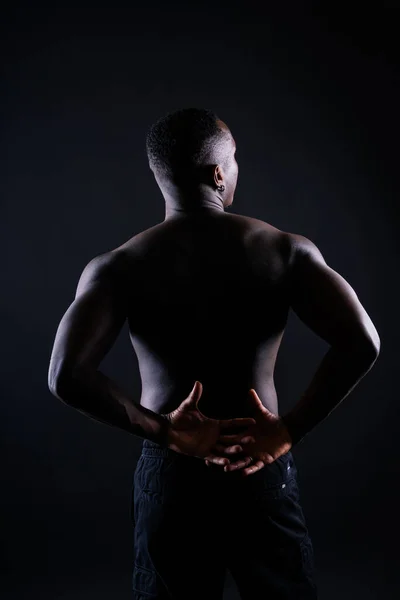 一个年轻的非洲肌肉发达的男人赤身裸体站在黑色背景下 — 图库照片