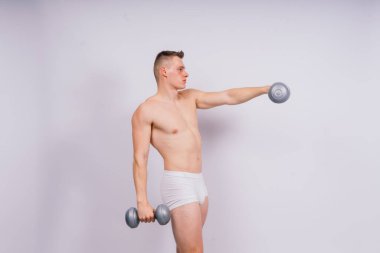 Shirtless bodybuilder holding a dumbell and showing his muscular arms.