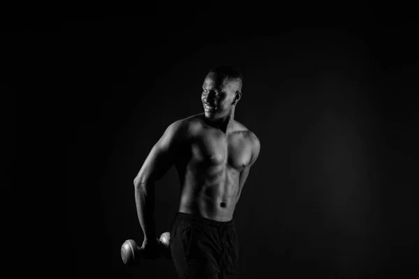 孤立的非洲肌肉男人 哑铃在黑暗的工作室背景 强壮的没穿上衣的黑人 — 图库照片