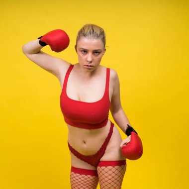 Baştan çıkarıcı genç ve formda bir bayan boksör. Stüdyoda eldiven giymiş.
