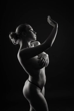 Üstsüz, şehvetli, beyaz kadın. Siyah bir arkaplanda.
