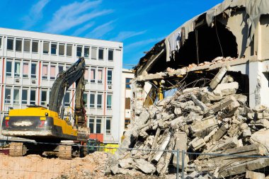 Demolition of a old building with sloopkraan against blue clouds sky.