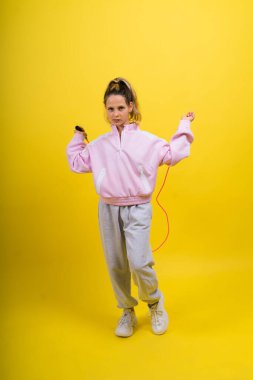 Adorable female child with skipping rope jumping in a studio