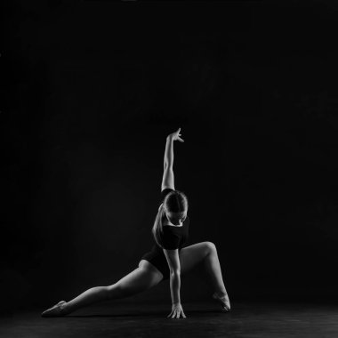 Uzun boylu, gülümseyen, spor yapan, beyaz ve koyu bir arka planda izole edilmiş genç kız.