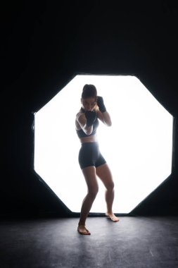 Woman Boxer In Gloves Training On a black, red, yellow Background