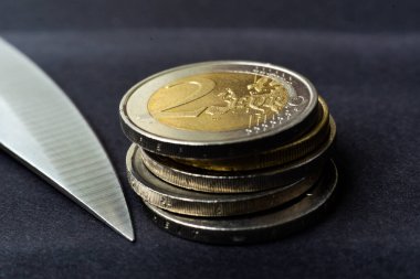 Avro sikkeye, hesap makinesine bıçak saplanmış. Tasarruf indirimi, para işi, suç. Makro.