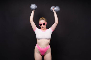 Baştan çıkarıcı güzel fitness kadını, halterlerle çalışan atletik kadın. Bir stüdyoda izole edilmiş.